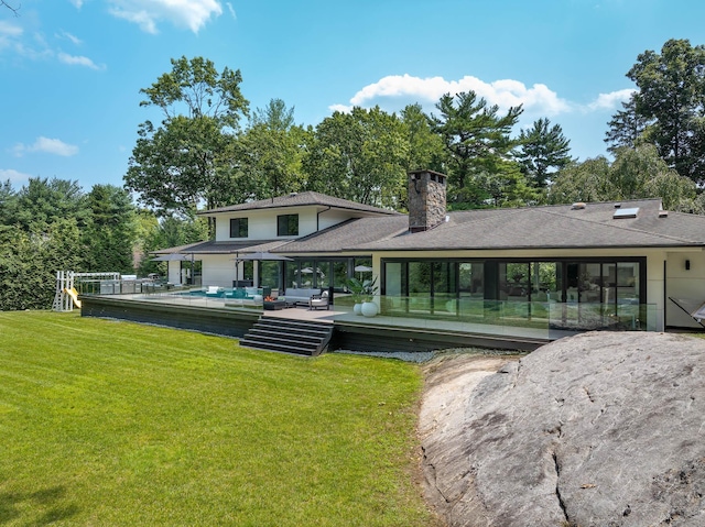 back of house featuring a chimney, a yard, an outdoor living space, and a wooden deck