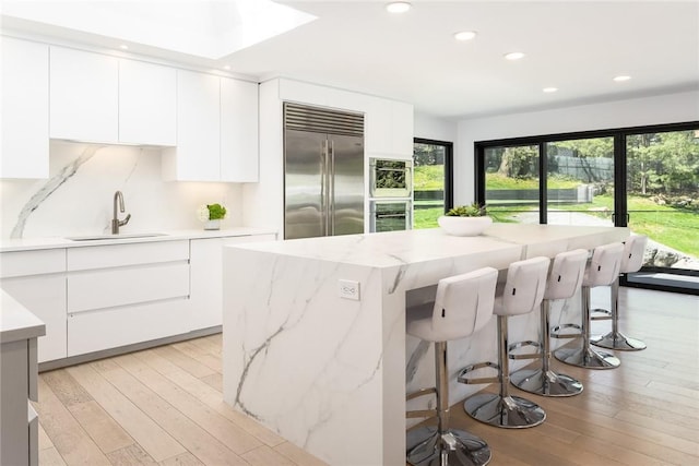 kitchen featuring stainless steel appliances, modern cabinets, a sink, and white cabinetry