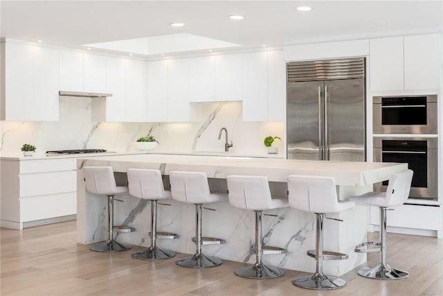 kitchen with appliances with stainless steel finishes, white cabinets, light countertops, and a breakfast bar area