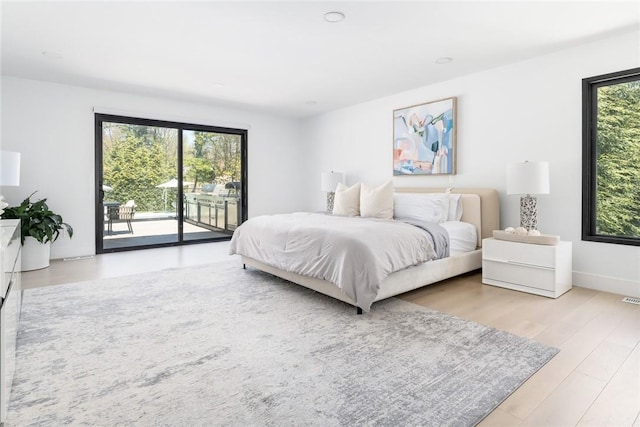 bedroom with light wood finished floors, access to outside, multiple windows, and baseboards