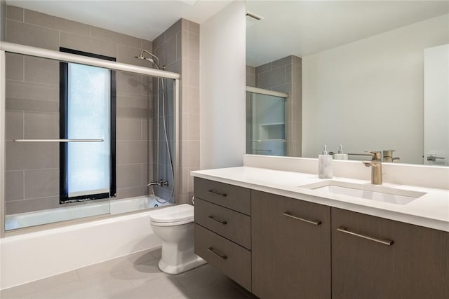 bathroom featuring tile patterned flooring, enclosed tub / shower combo, vanity, and toilet