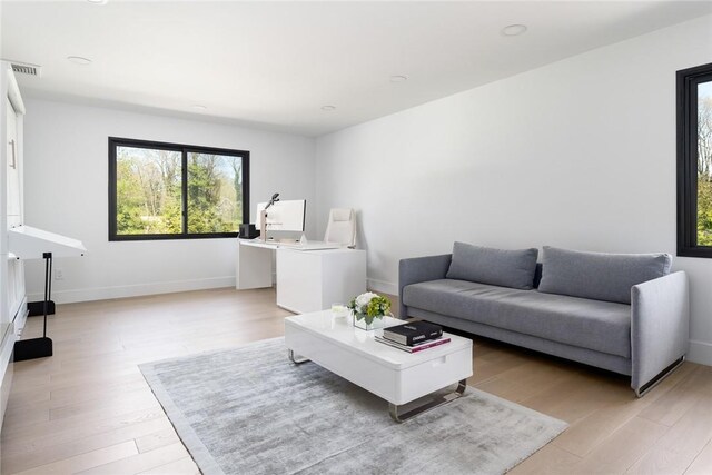 living room with light wood-style flooring, visible vents, and baseboards