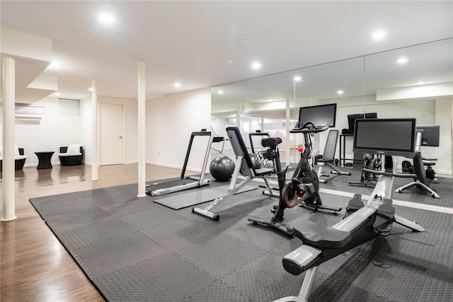 exercise room featuring recessed lighting, an AC wall unit, and baseboards