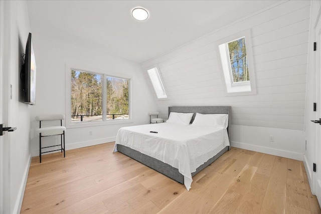 bedroom featuring light wood-style floors, a skylight, and baseboards