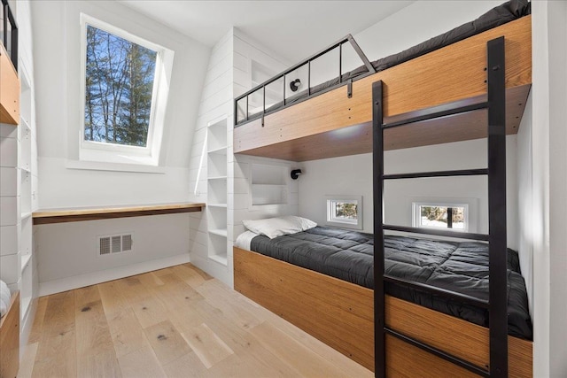 bedroom with light wood-style floors and visible vents