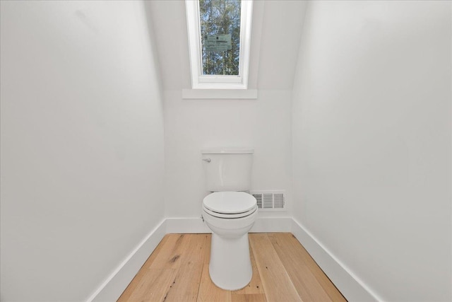 bathroom with toilet, wood finished floors, visible vents, and baseboards