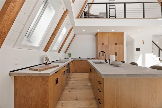 kitchen with an island with sink, modern cabinets, light countertops, high vaulted ceiling, and a sink