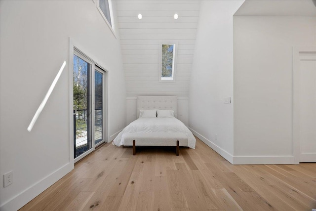 unfurnished bedroom featuring baseboards, a towering ceiling, and light wood-style floors