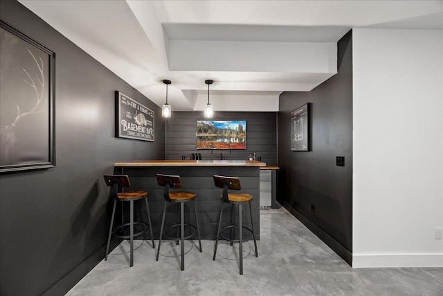 bar with baseboards, hanging light fixtures, indoor wet bar, and finished concrete floors