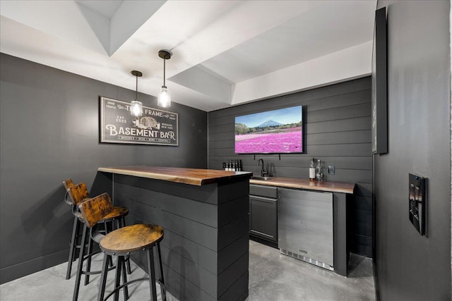 bar with indoor wet bar, hanging light fixtures, a sink, concrete flooring, and fridge