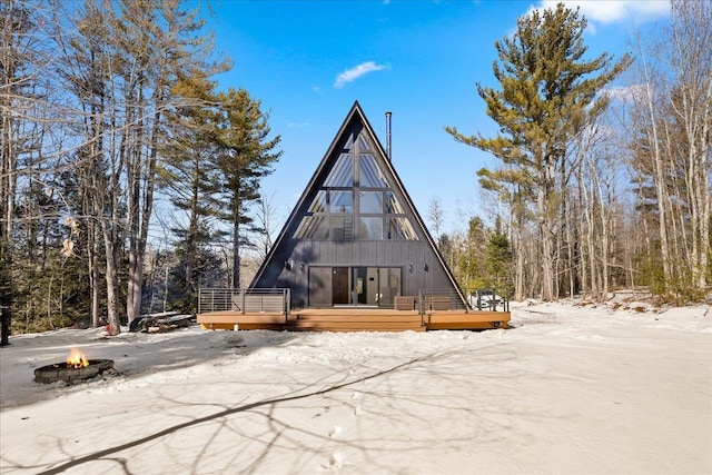 snow covered house with a fire pit and a wooden deck