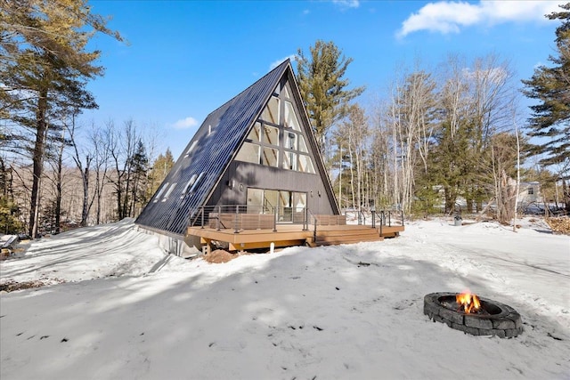 snow covered property featuring metal roof, a fire pit, and a wooden deck