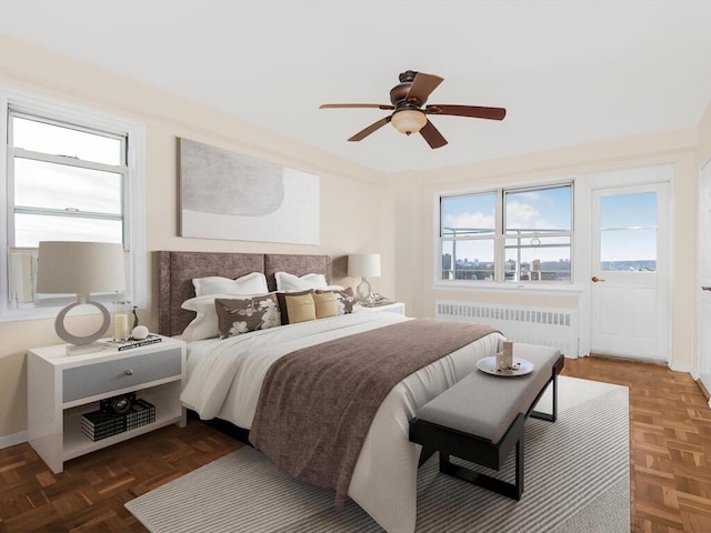 bedroom featuring a ceiling fan, multiple windows, and radiator heating unit