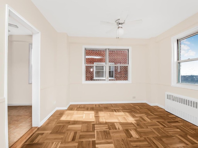 spare room featuring radiator, ceiling fan, and baseboards