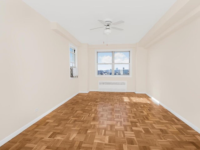 spare room featuring radiator, baseboards, and a ceiling fan