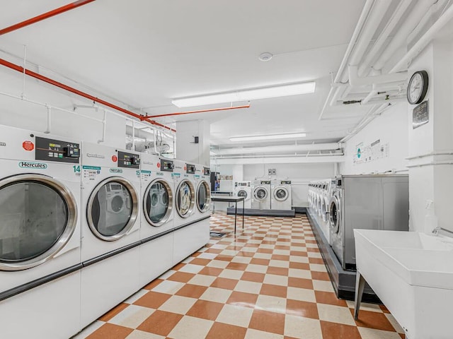 common laundry area with a garage, a sink, washer and clothes dryer, and light floors