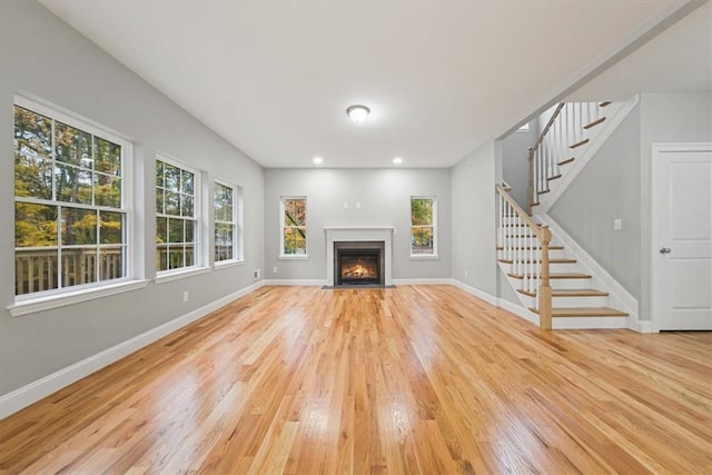 unfurnished living room featuring light wood-style floors, baseboards, and stairs