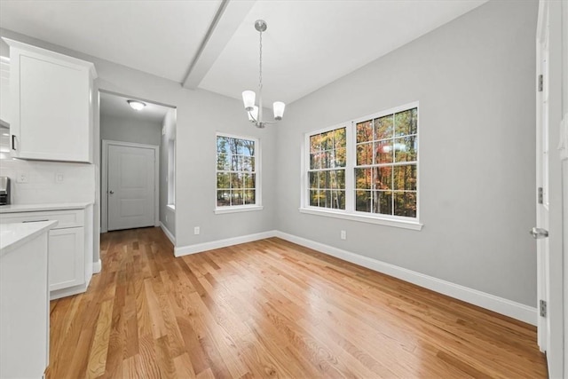 unfurnished dining area featuring light wood-type flooring, baseboards, and a notable chandelier