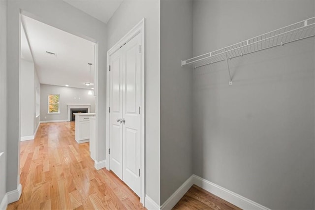 corridor featuring baseboards, visible vents, and light wood-style floors