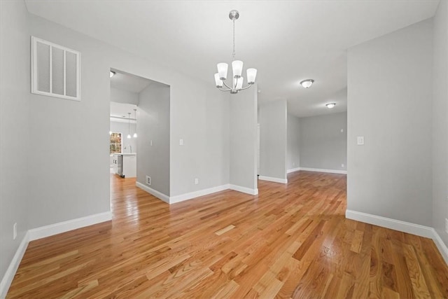 unfurnished dining area featuring light wood-style floors, baseboards, visible vents, and an inviting chandelier