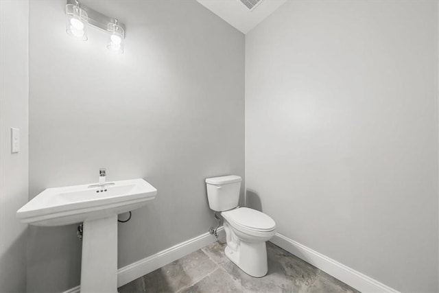 bathroom with a sink, toilet, and baseboards