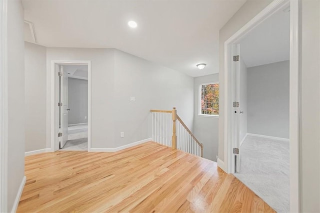 hall with baseboards, an upstairs landing, and wood finished floors