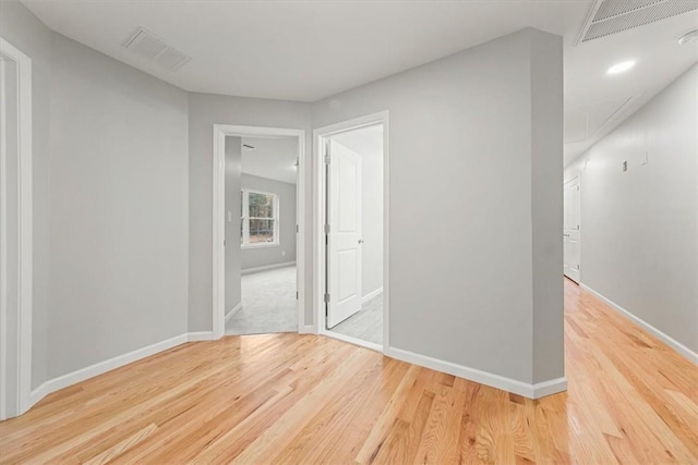 spare room featuring light wood-style floors, attic access, visible vents, and baseboards