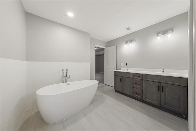 full bathroom with a freestanding tub, visible vents, a sink, and double vanity