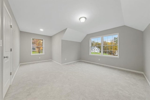 additional living space featuring lofted ceiling, light colored carpet, and baseboards