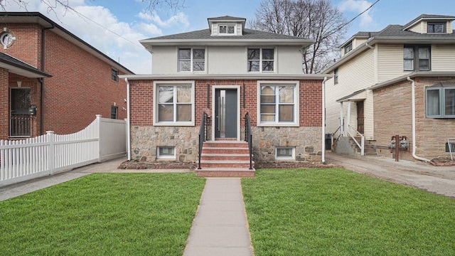 american foursquare style home with stone siding, a front yard, and fence