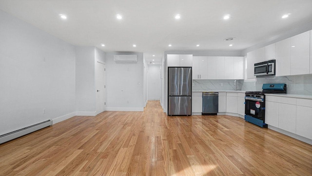 kitchen with stainless steel appliances, a wall mounted air conditioner, light countertops, and white cabinetry