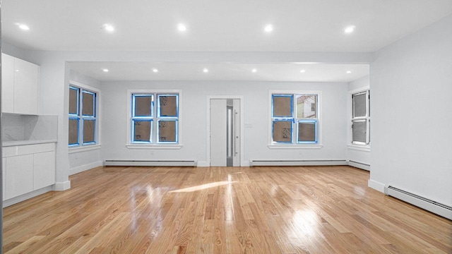 unfurnished living room with light wood finished floors, baseboard heating, and recessed lighting