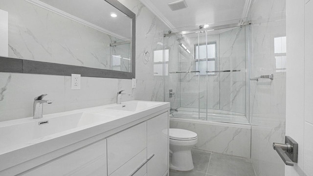 bathroom featuring enclosed tub / shower combo, a sink, visible vents, tile walls, and crown molding