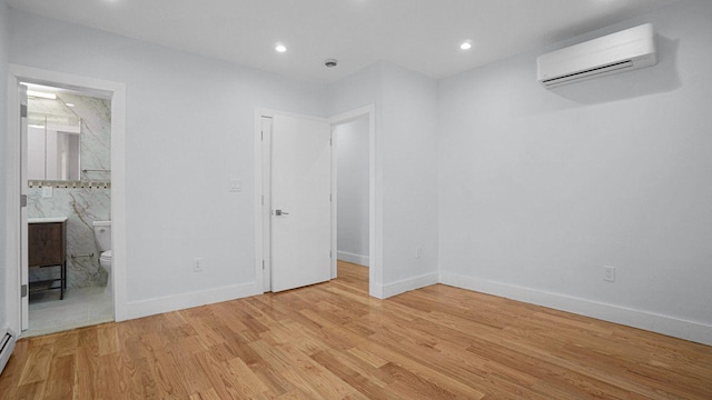 unfurnished bedroom featuring recessed lighting, an AC wall unit, light wood-style flooring, and baseboards