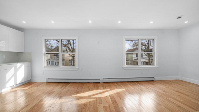 unfurnished dining area featuring light wood-type flooring, a healthy amount of sunlight, baseboard heating, and recessed lighting