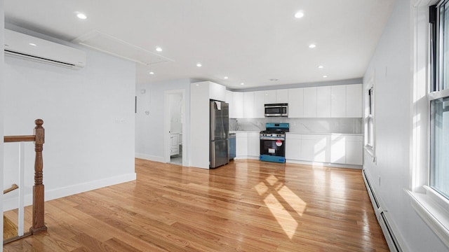 unfurnished living room with attic access, light wood-style flooring, an AC wall unit, and recessed lighting