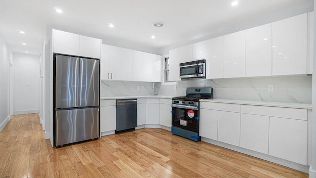 kitchen with modern cabinets, appliances with stainless steel finishes, white cabinets, and light countertops