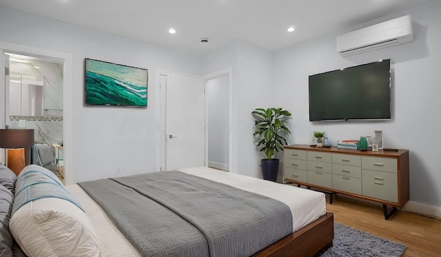 bedroom featuring baseboards, ensuite bath, an AC wall unit, light wood-type flooring, and recessed lighting