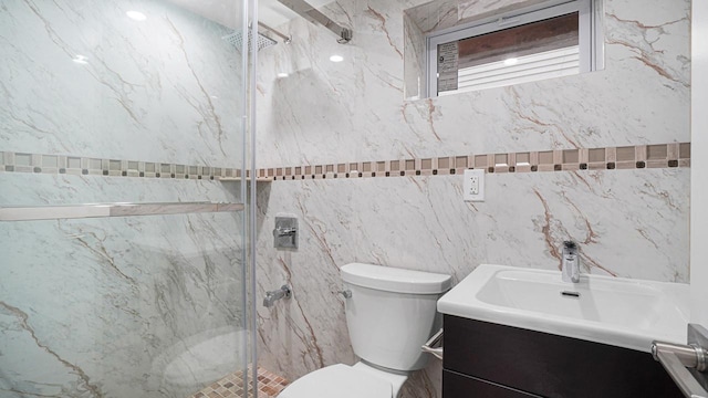 bathroom with toilet, a shower stall, vanity, and tile walls