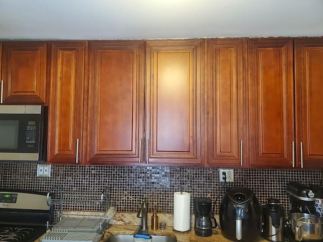 room details featuring a sink, brown cabinetry, stainless steel appliances, and decorative backsplash