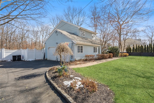 view of home's exterior with aphalt driveway, a yard, fence, and an attached garage