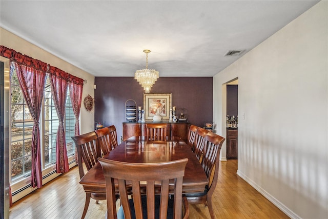 dining space featuring a chandelier, visible vents, baseboards, baseboard heating, and light wood-type flooring