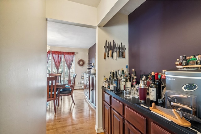 bar featuring light wood-type flooring, baseboard heating, and a dry bar