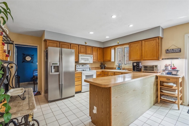 kitchen featuring light countertops, white appliances, a peninsula, and light tile patterned flooring