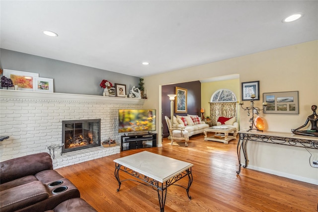 living room with recessed lighting, baseboards, a fireplace, and light wood finished floors