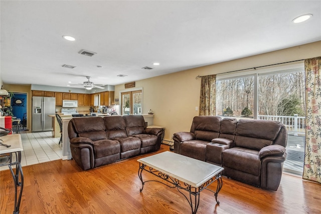 living area with a healthy amount of sunlight, light wood finished floors, and visible vents