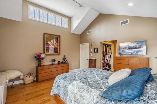 bedroom featuring light wood-type flooring, visible vents, a walk in closet, and a closet