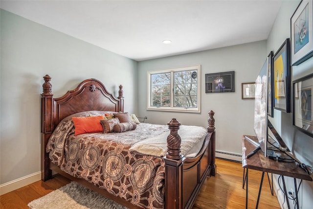 bedroom featuring baseboard heating, light wood-type flooring, and baseboards