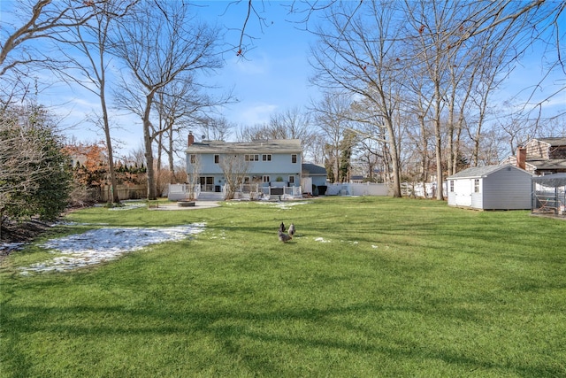 view of yard with a storage shed, a fenced backyard, a patio, and an outbuilding