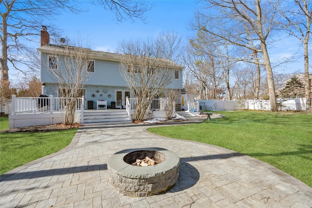 back of house with a fire pit, fence, a yard, driveway, and a wooden deck